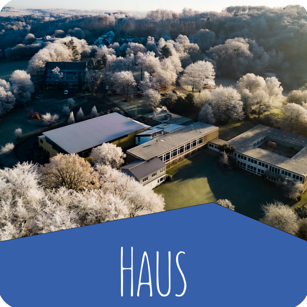 Luftaufnahme eines Gebäudes im Winter mit verschneiter Landschaft und Schriftzug „Haus“ – Evangelische Gesellschaft für Deutschland KdöR