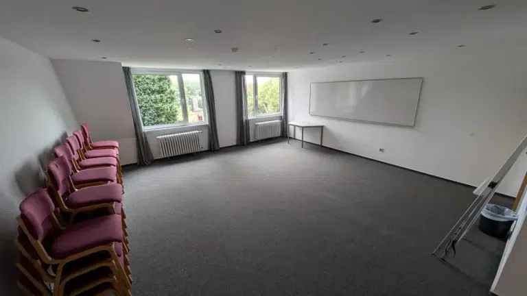 Großer leerer Seminarraum mit Teppichboden und Whiteboard an der Wand – Evangelische Gesellschaft für Deutschland KdöR
